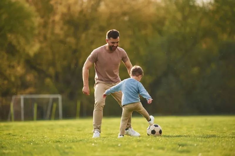 Apprentissage du football. Père heureux avec son fils s'amusant sur le terrain en été.