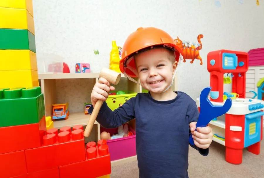 Petit réparateur rigolo avec un marteau et une clé à molette dans la chambre d'enfant